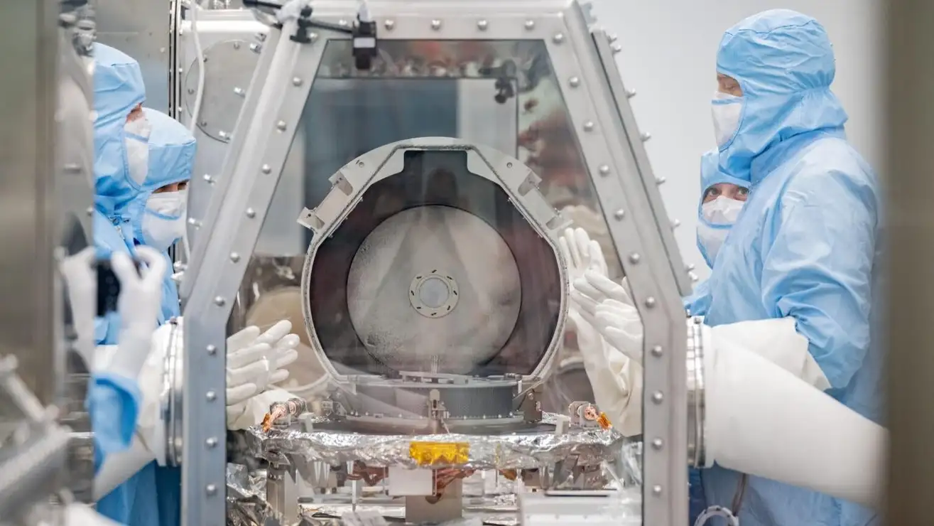 Membros da equipe de curadoria da NASA, juntamente com especialistas em recuperação da Lockheed Martin, removendo a tampa do recipiente.